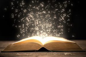Open book and magical glowing letters.